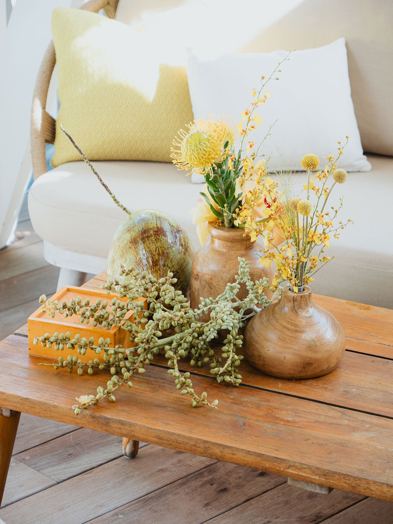 Natural floral arrangement with yellow flowers and greenery on a wooden table for a tropical event in St Barth.