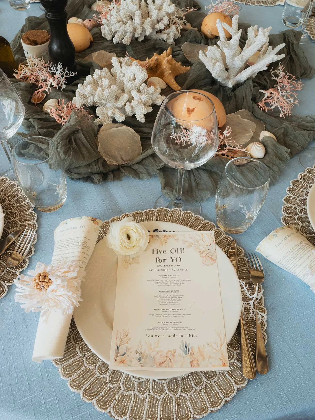 Coastal-inspired wedding table with blue linens, seashells, candles, and elegant decor in St Barth.