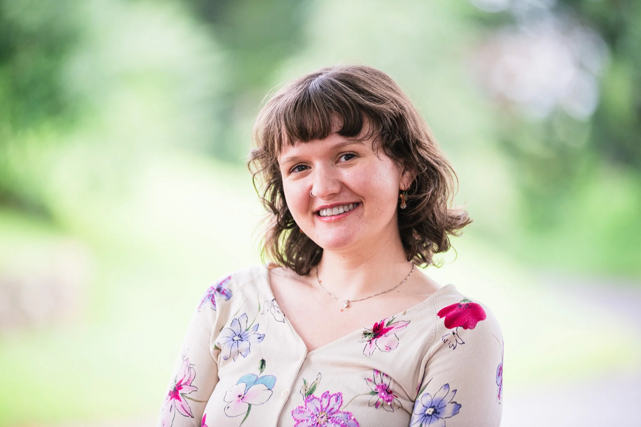 A smiling woman with short brown hair and a shirt with flowers on it