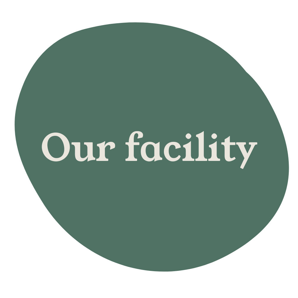 Green circular sign with the text 'Our facility' in white.