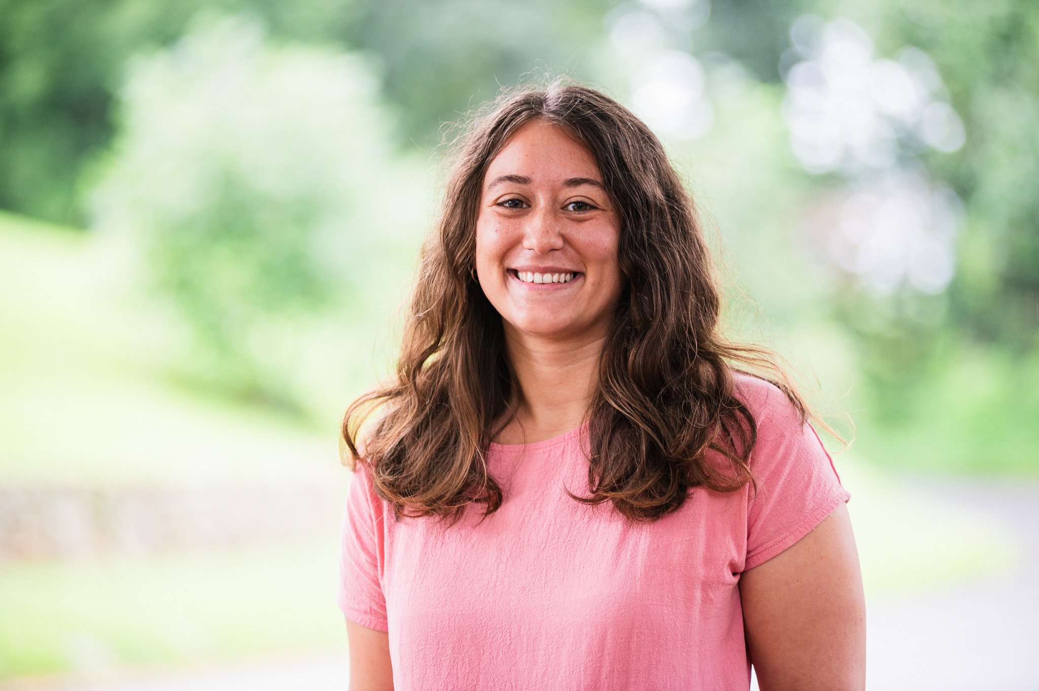 Woman with brown wavy hair and a pink shirt