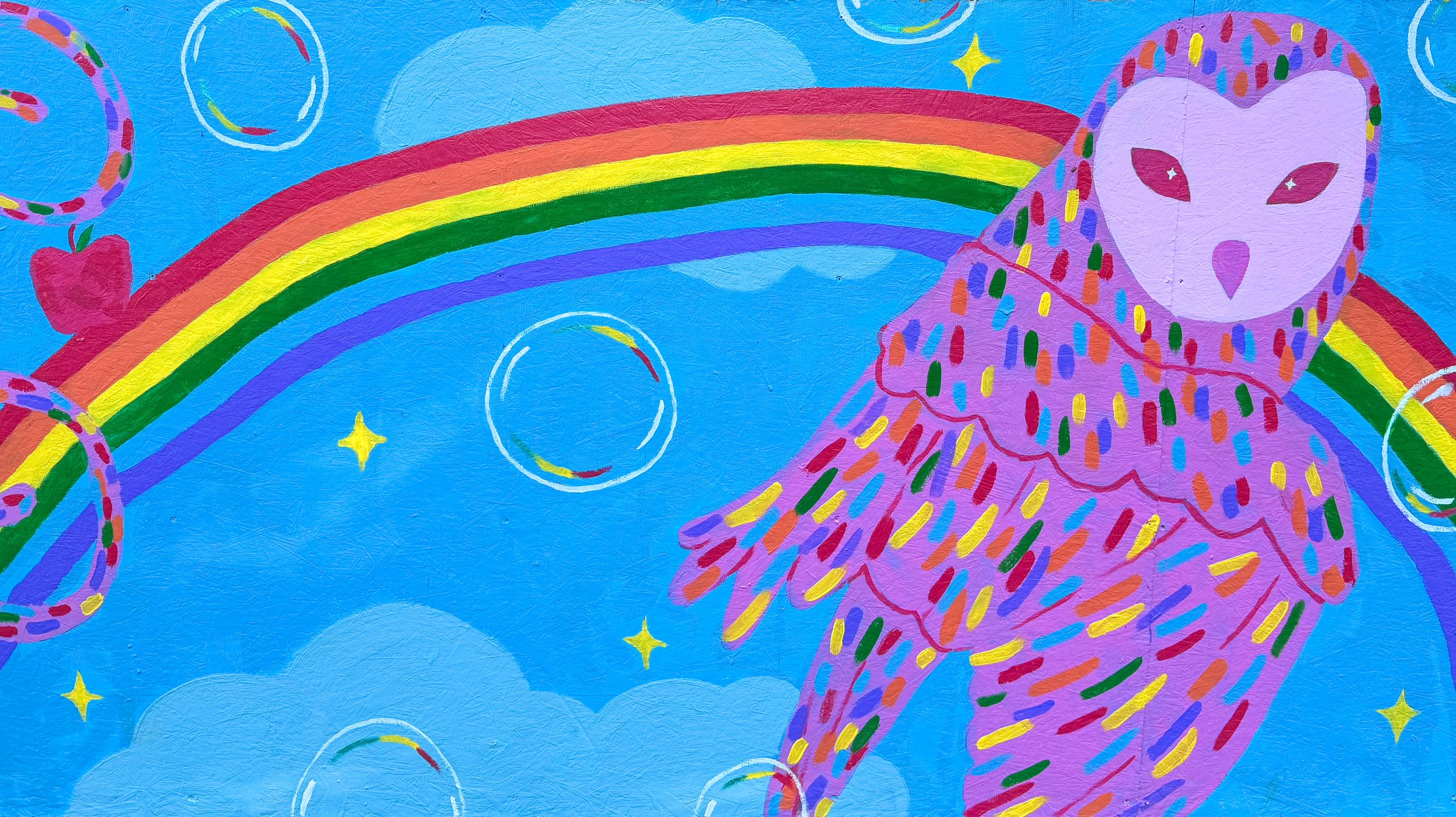 A colorful mural featuring a rainbow, clouds, stars, bubbles, and a figure wearing a purple outfit covered in multicolored dashes, with a simplified face mask and face with eyes and a nose.