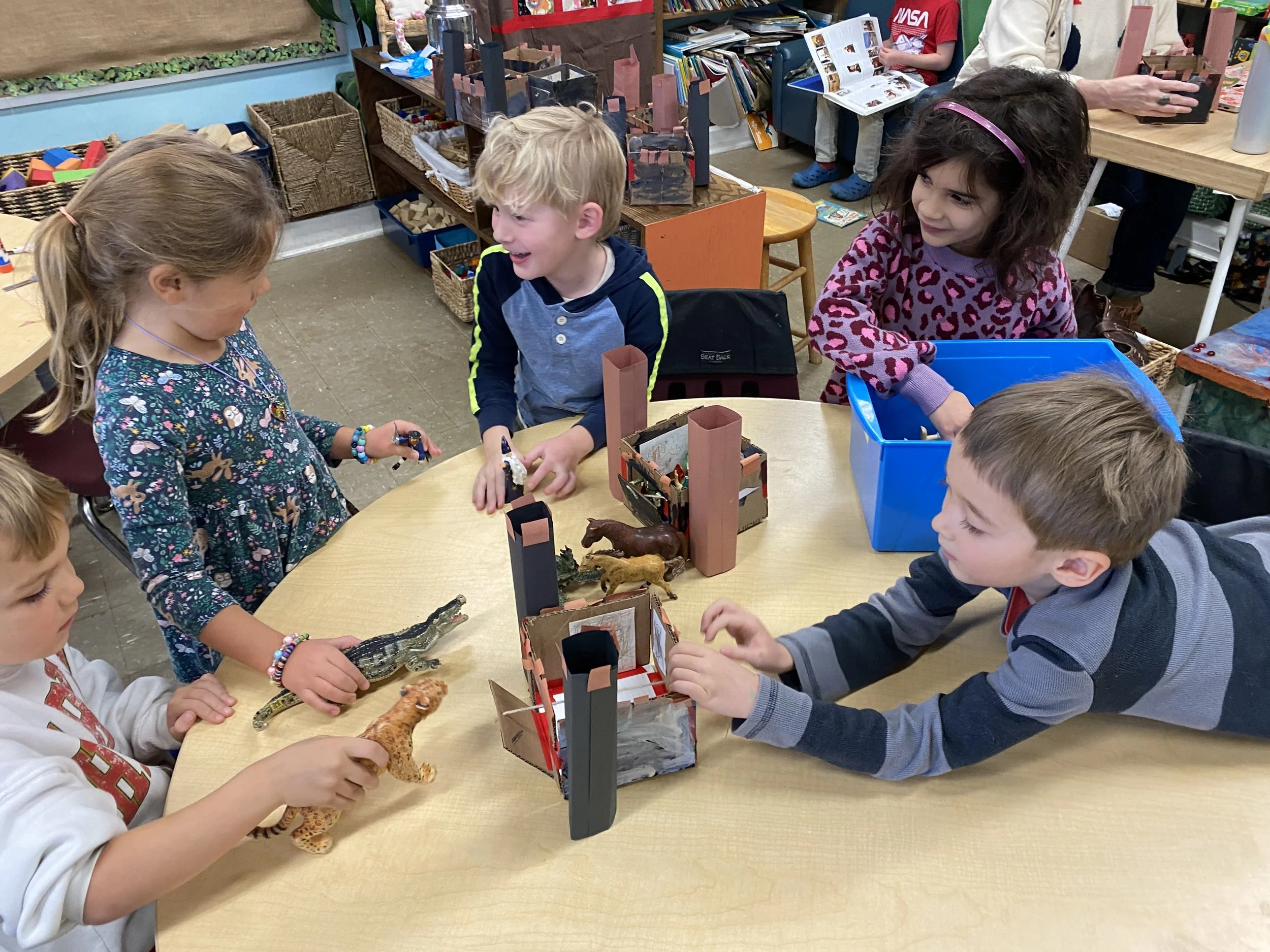 Children playing with toy animals in a classroom.