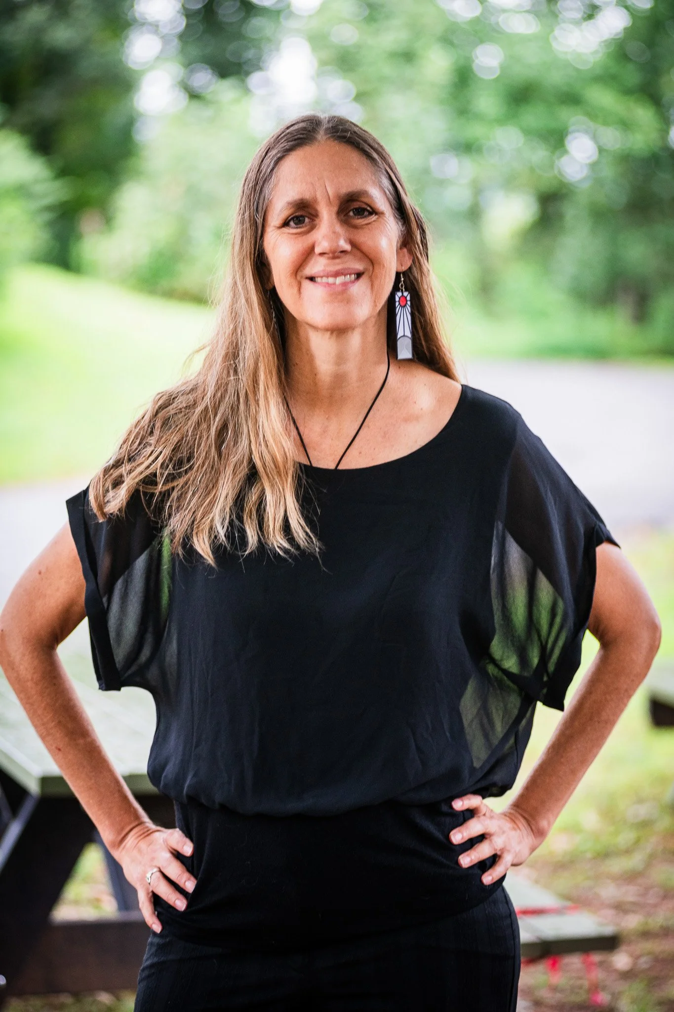 A woman in a forested setting smiling peacefully in a portrait