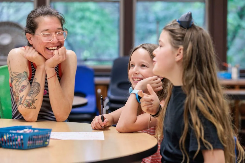 laughing teacher listening to elementary students