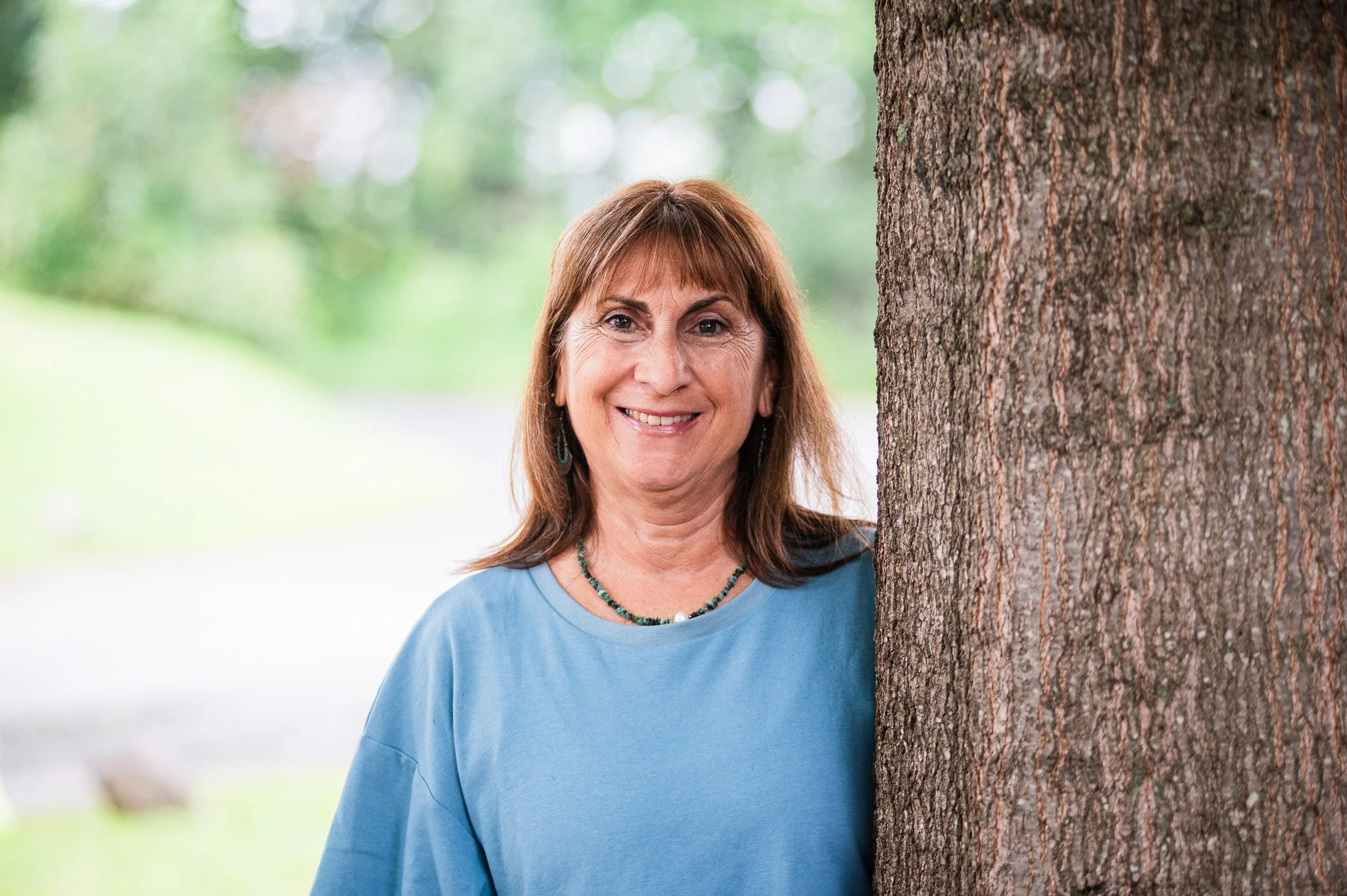 Woman with brown hair, a green necklace, and a blue shirt