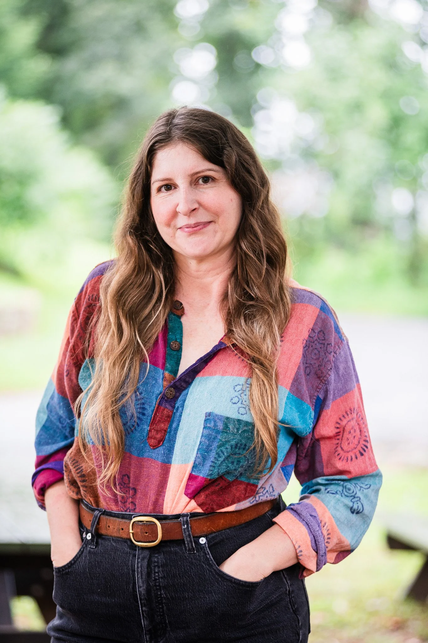 portrait of a woman with long brown hair in an artistic patchwork smock shirt