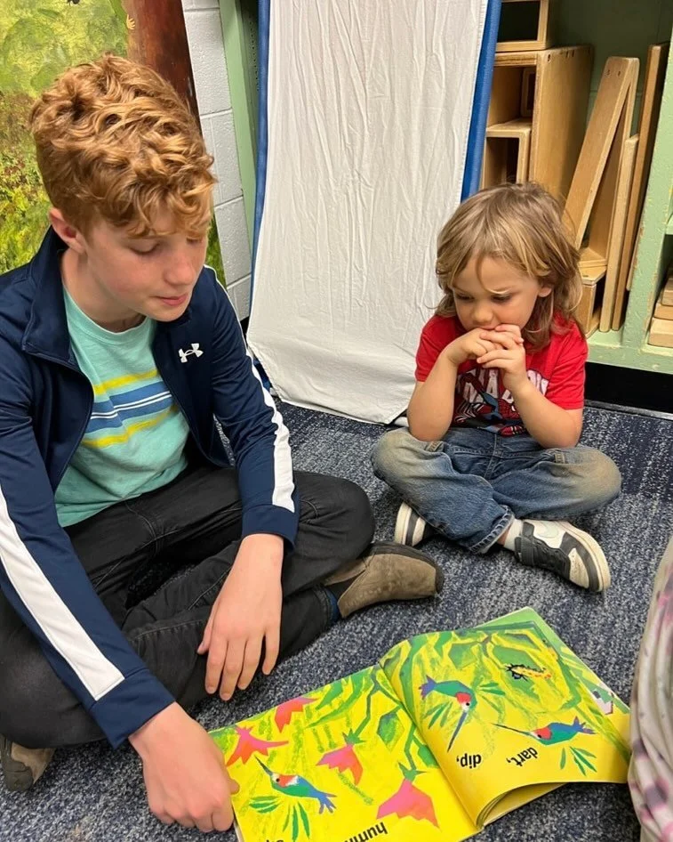 a middle school boy reads to his pre-k buddy