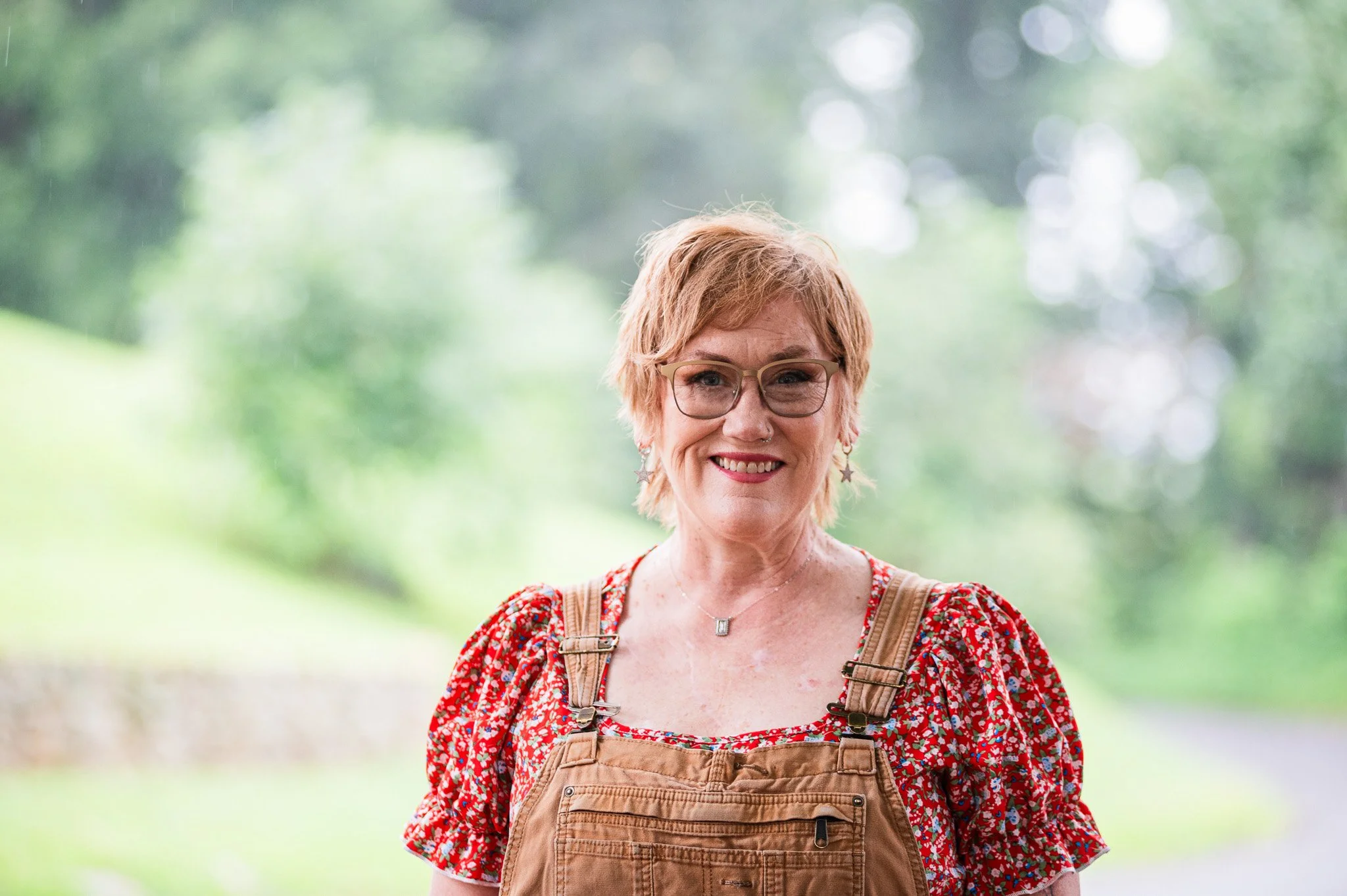 A woman in overalls and short red hair smiling