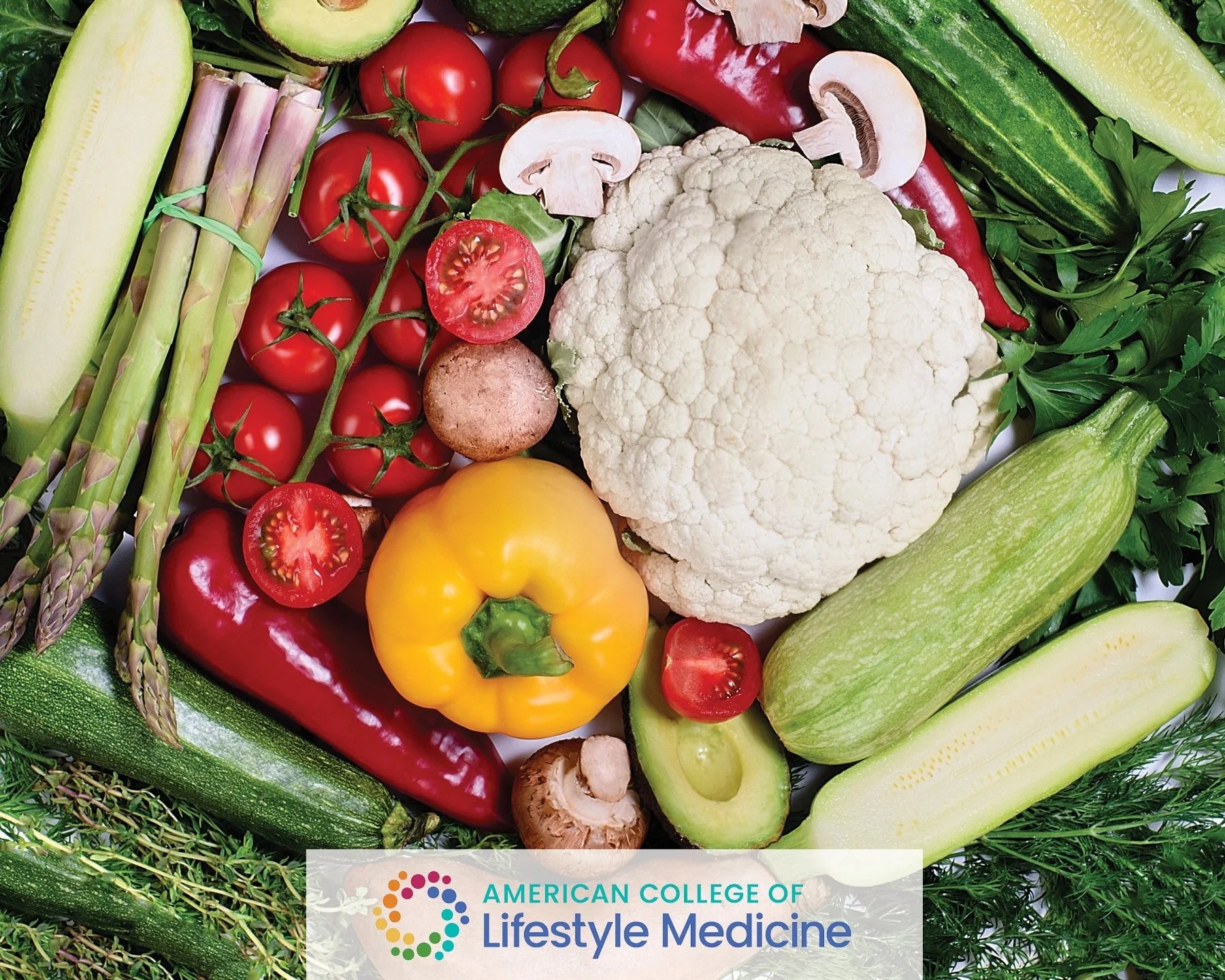 A variety of fresh vegetables including cherry tomatoes, cauliflower, red and yellow bell peppers, zucchini, cucumber, mushrooms, asparagus, and leafy greens displayed together.