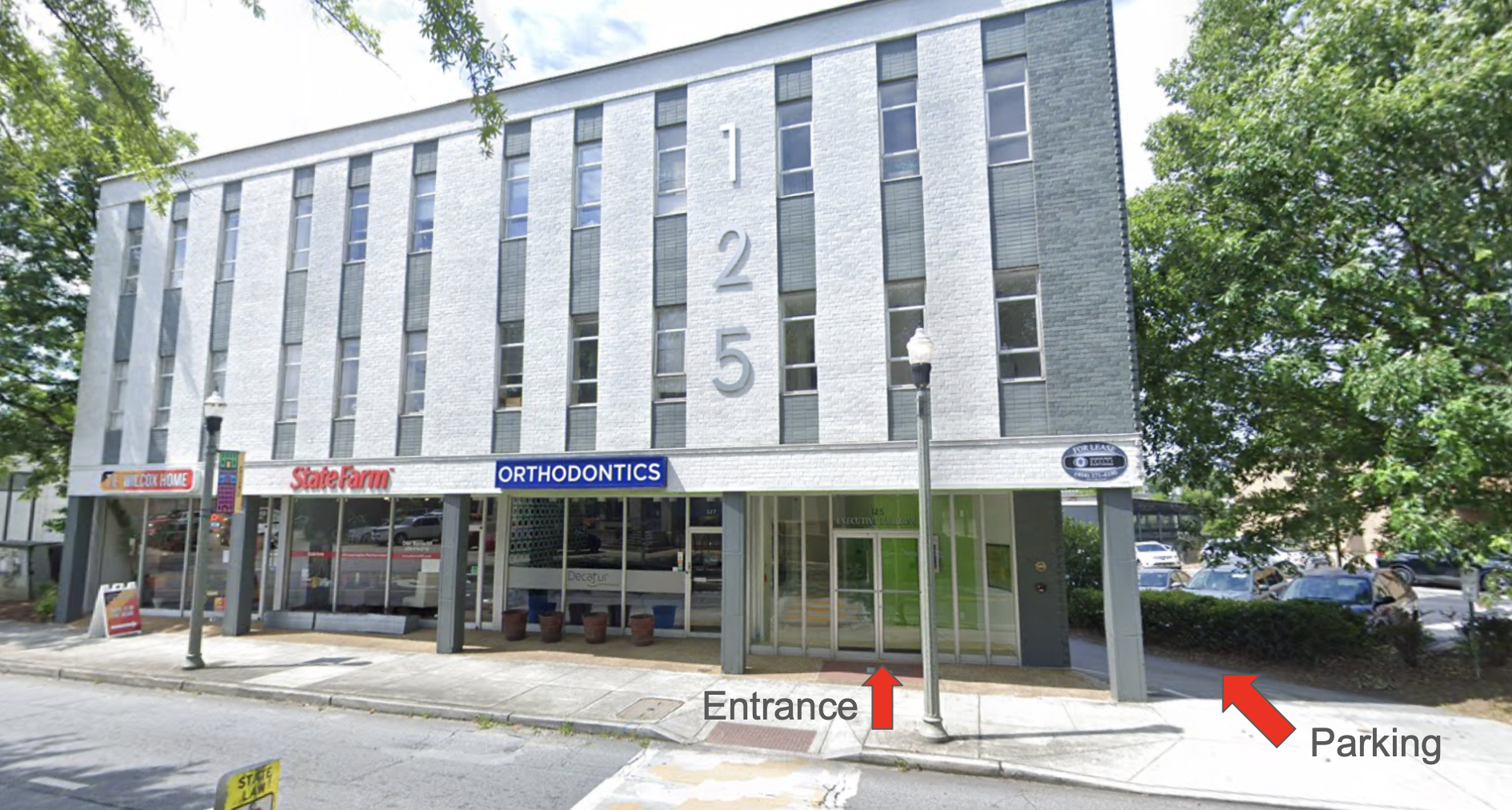 A multi-story building with white brick exterior, large numbers '125' on the front, and storefronts on the ground level including a State Farm office and orthodontics clinic. An entrance is marked with a red arrow, and parking is indicated with a red arrow on the right, with trees and parked cars around.