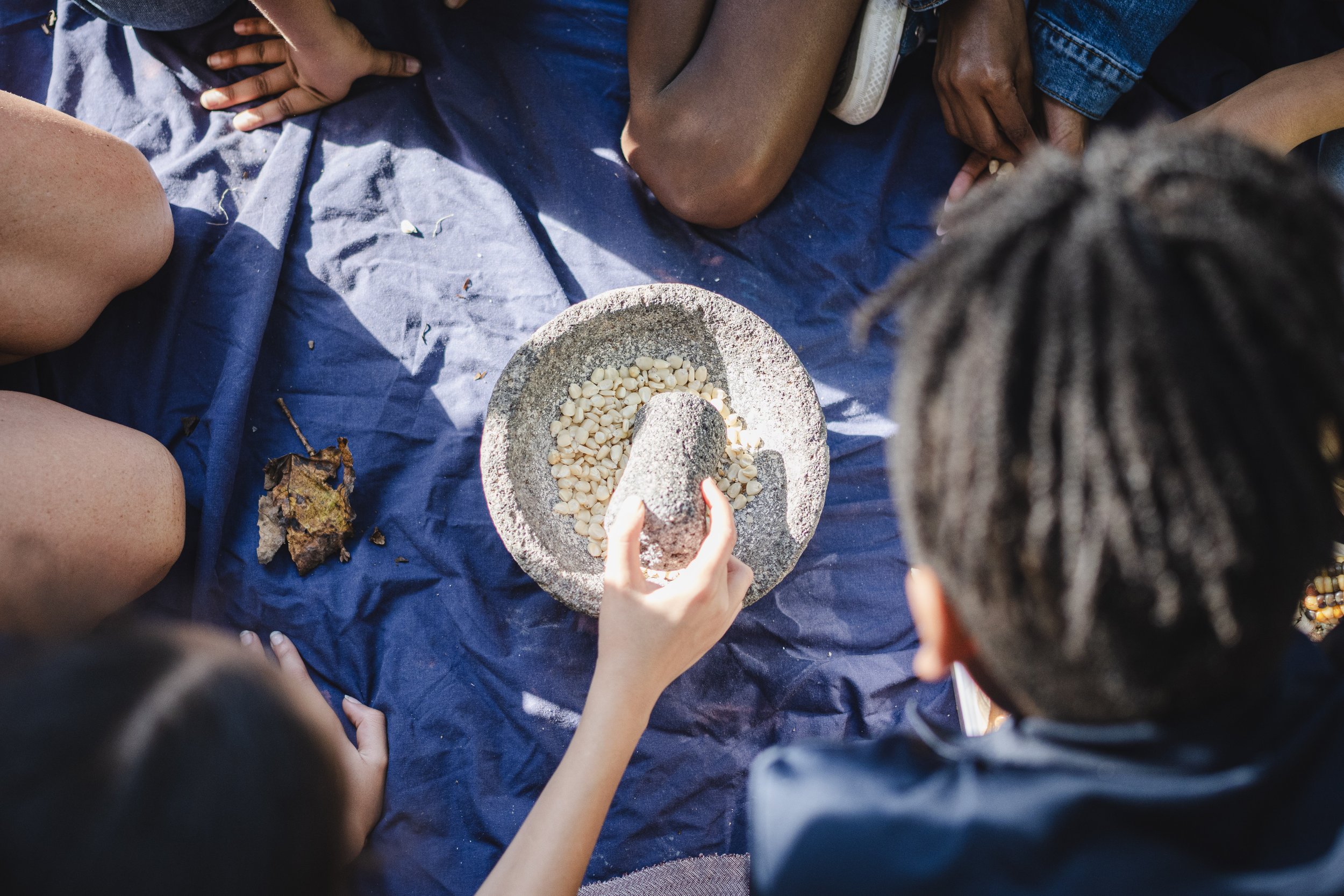 group of kids use a mortar and pestle