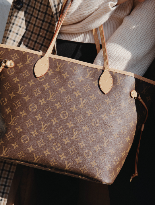 Borsa Louis Vuitton con monogramma, manici in pelle beige, con persone che indossano cappotti a quadri e a maglia