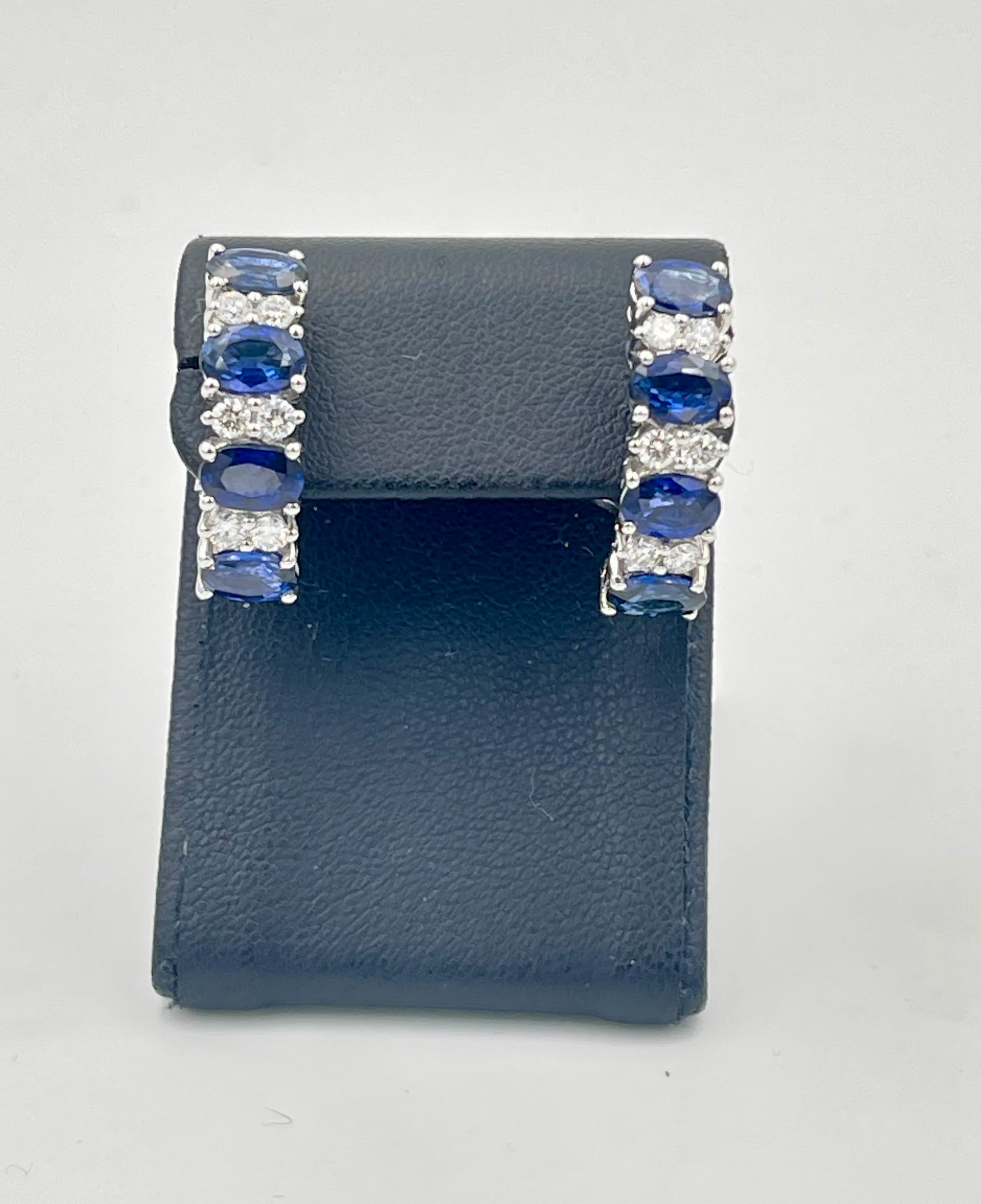 Orecchini in oro bianco 18K con zaffiri blu e diamanti su espositore