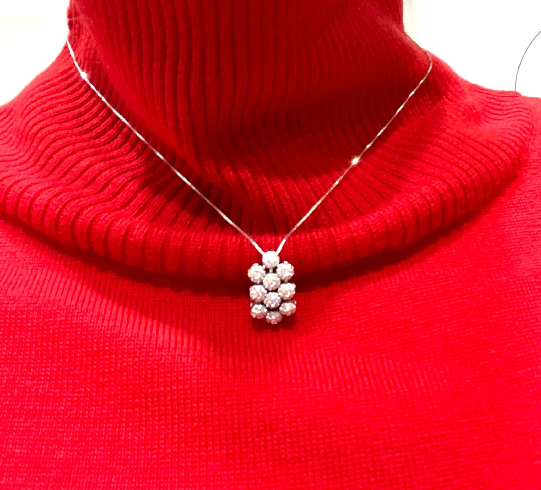 Collana con pendente a grappolo di brillanti su maglione rosso