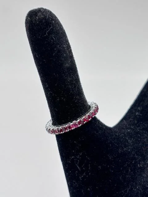 Anello eternity in oro bianco 18K con pietre rosse su espositore nero