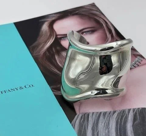 Bracciale rigido Tiffany in argento appoggiato su una rivista