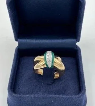 Anello in oro con pietre verdi, posizionato in una scatola blu.