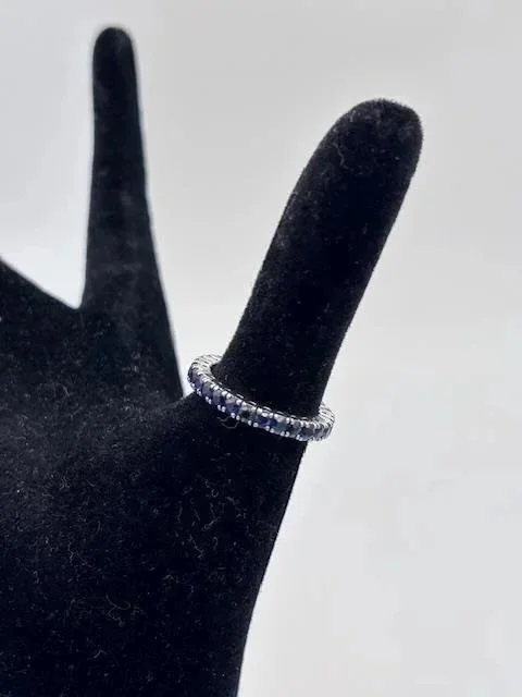 Anello eternity in oro bianco 18K con pietre preziose su espositore nero