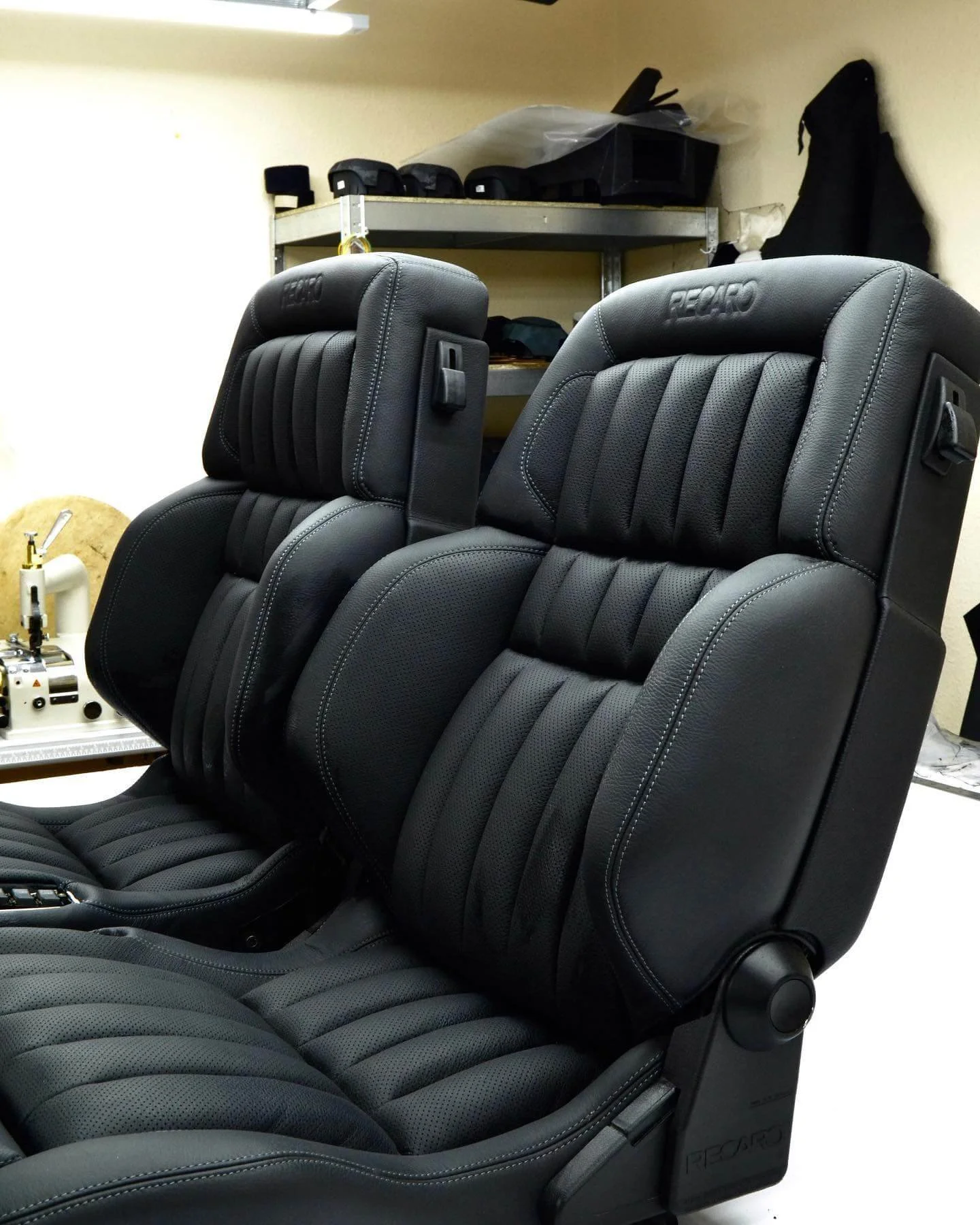 Пара чорних шкіряних сидінь Recaro: ортопедична форма, перфорація та біла декоративна строчка