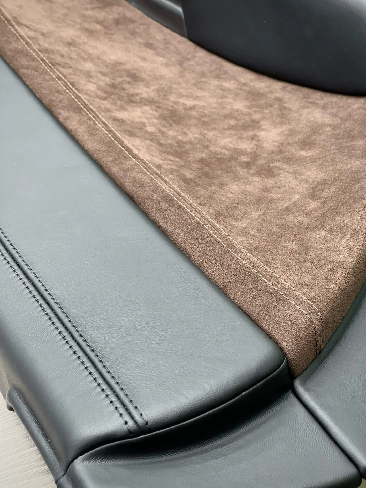 Макро фото якості шва: з'єднання чорної шкіри та коричневої замші подвійною строчкою