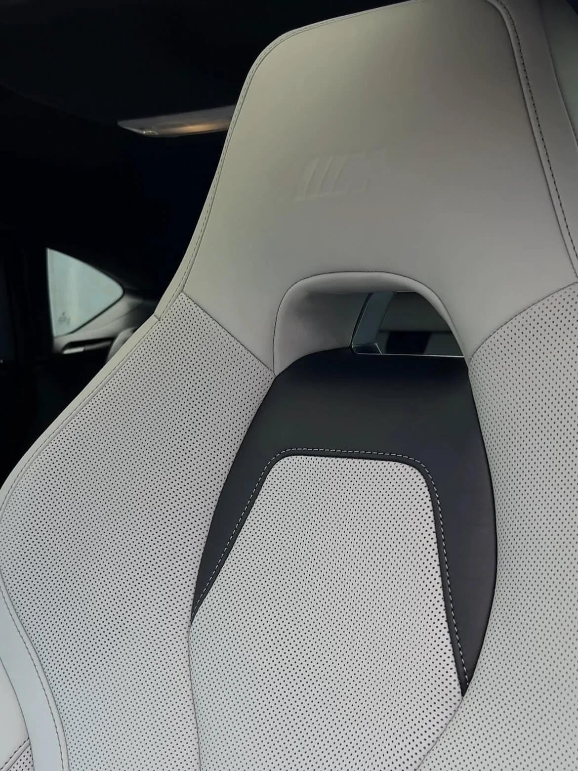 Деталь сидіння BMW M: тиснення логотипу на підголівнику, біла шкіра з перфорацією та чорна вставка