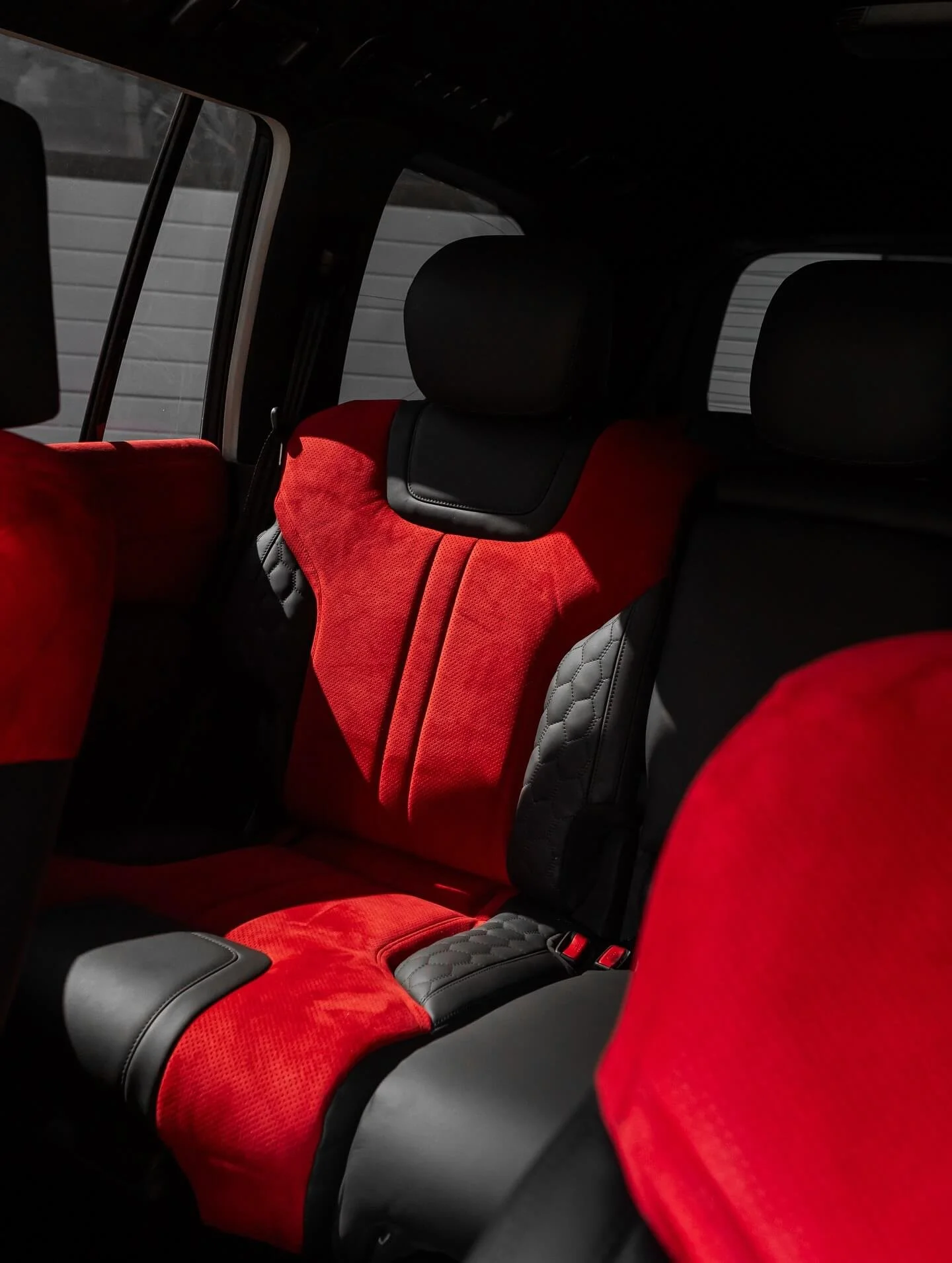 Задній ряд сидінь позашляховика, перешитий в яскраву червону алькантару з чорними шкіряними вставками