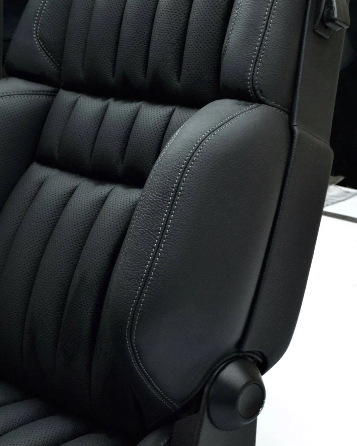 Макро фото бокової підтримки сидіння: текстура чорної шкіри та ідеальний подвійний шов