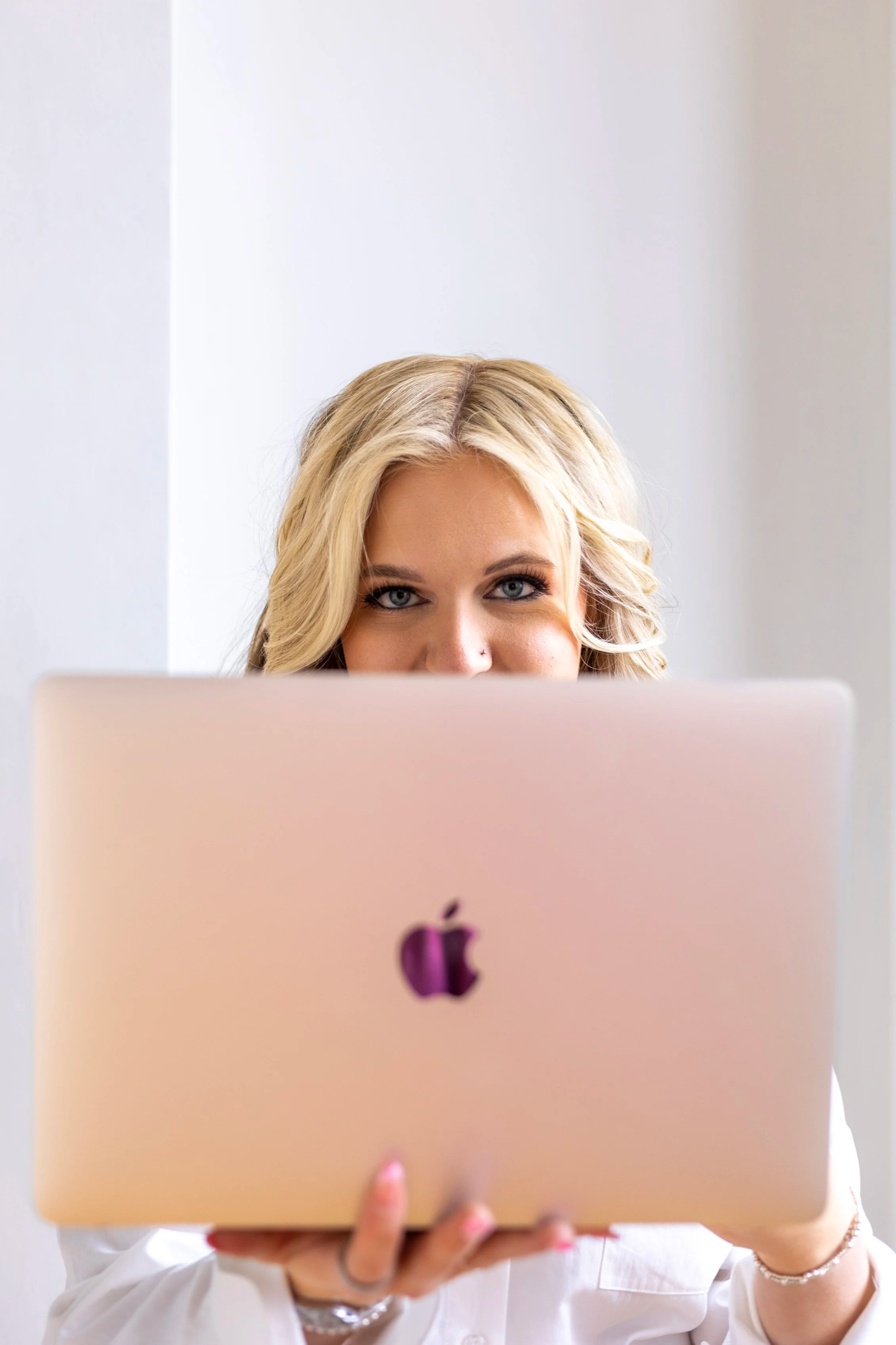 Clean workspace with a laptop, an iMac, a mouse on a leather mouse pad, a speech pen, a potted succulent, a water bottle, and a desk lamp, with natural light coming from behind.