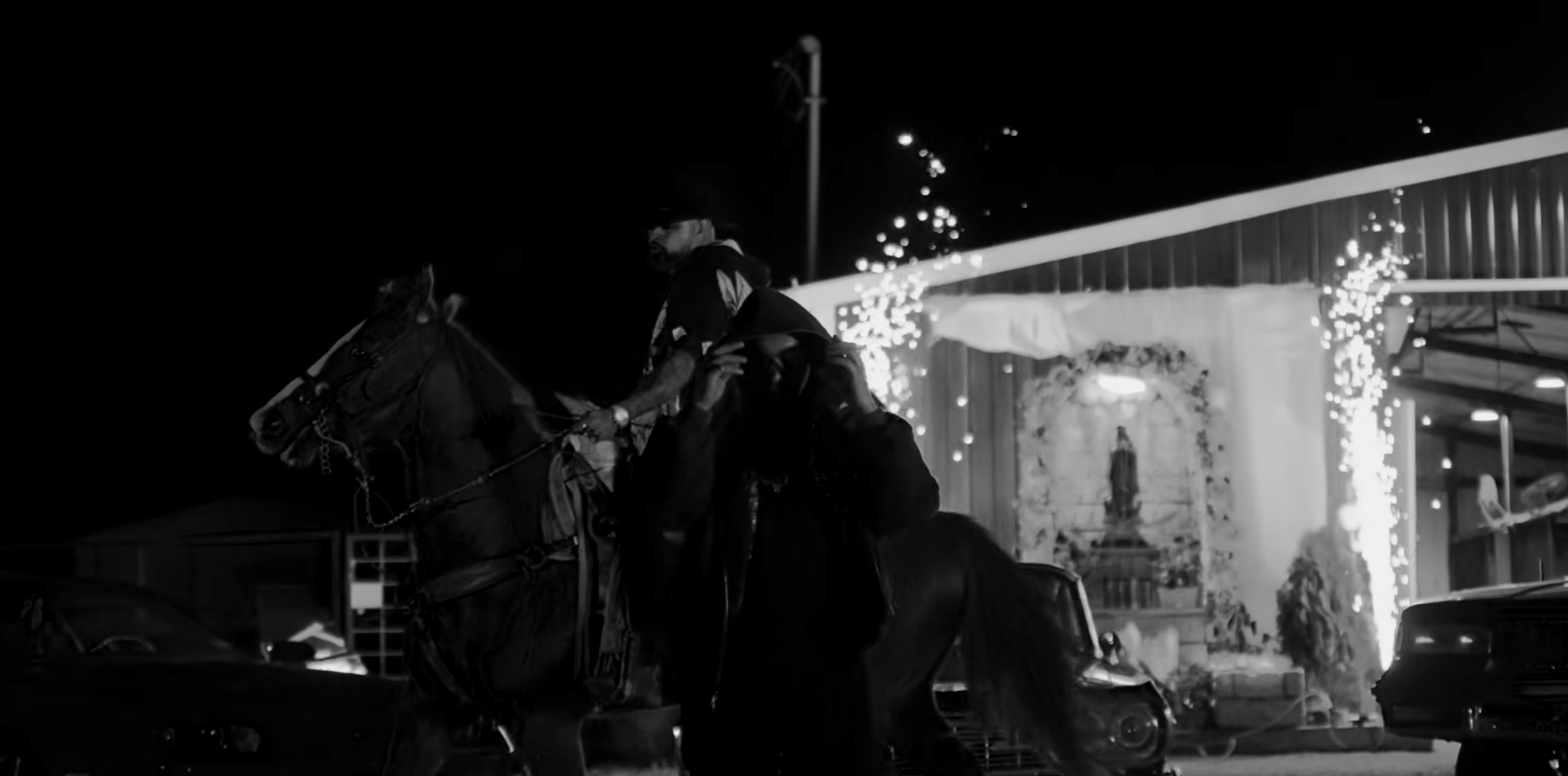 Night scene with a man on horseback in front of a building with bright lights and fireworks.