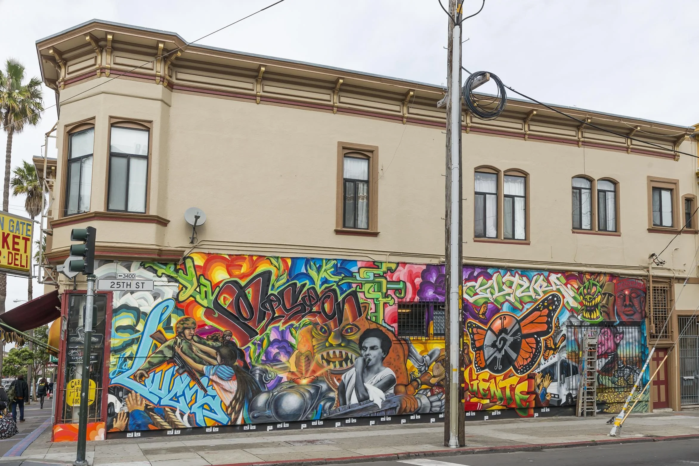 Colorful graffiti mural on a building wall at 25th Street, featuring various characters, a motorcycle, a butterfly, and vibrant abstract designs.