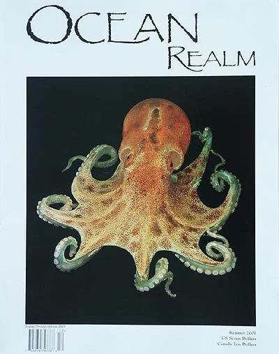 A magazine cover titled 'OCEAN REALM' featuring an octopus with reddish-brown and greenish tentacles against a black background.