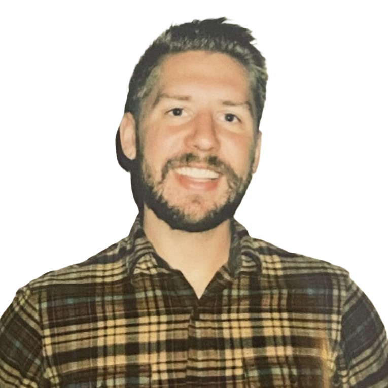Luc Gensler, a man with a beard and mustache wearing a plaid shirt, smiling.