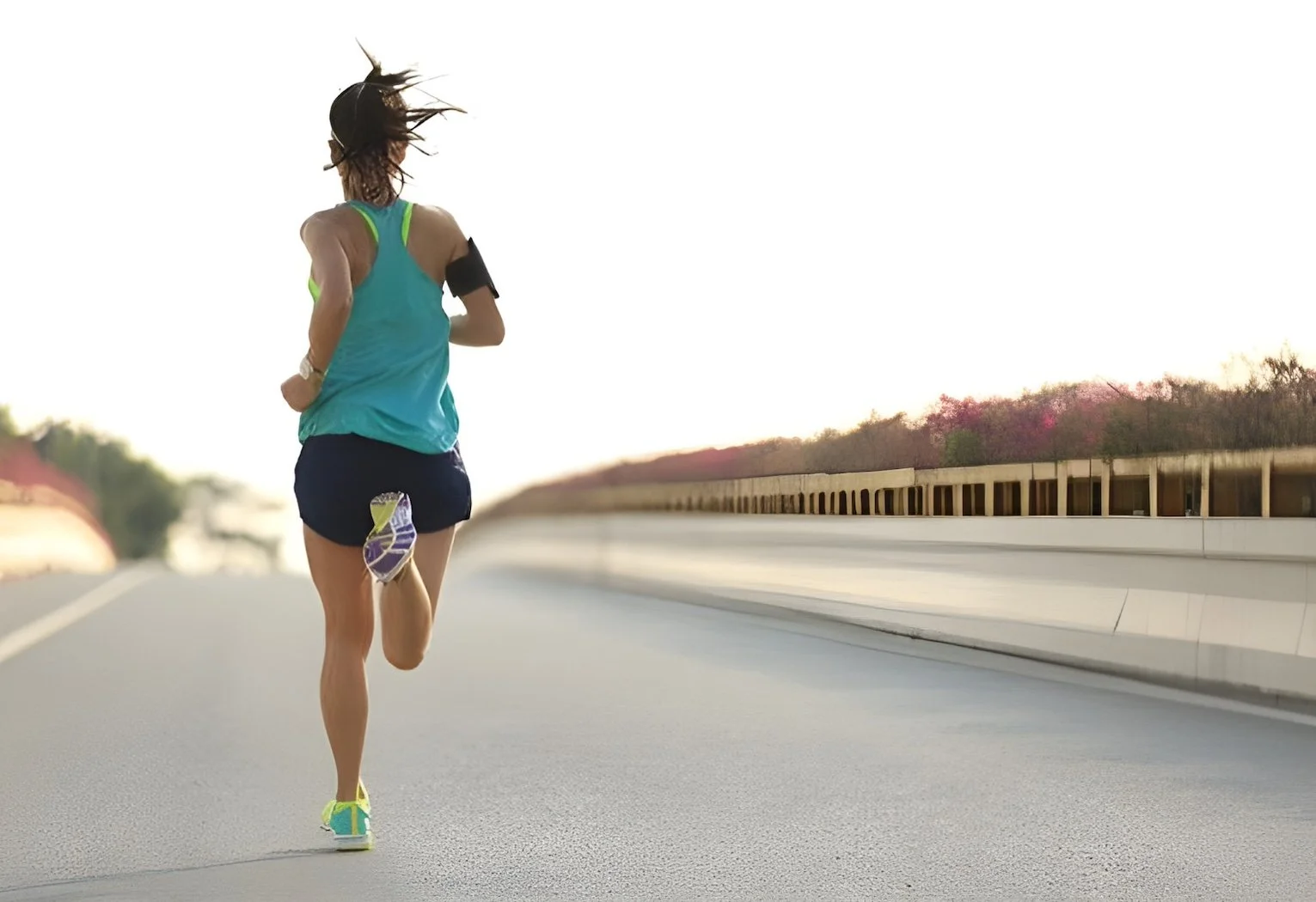 A woman running on an empty road during sunset or sunrise.