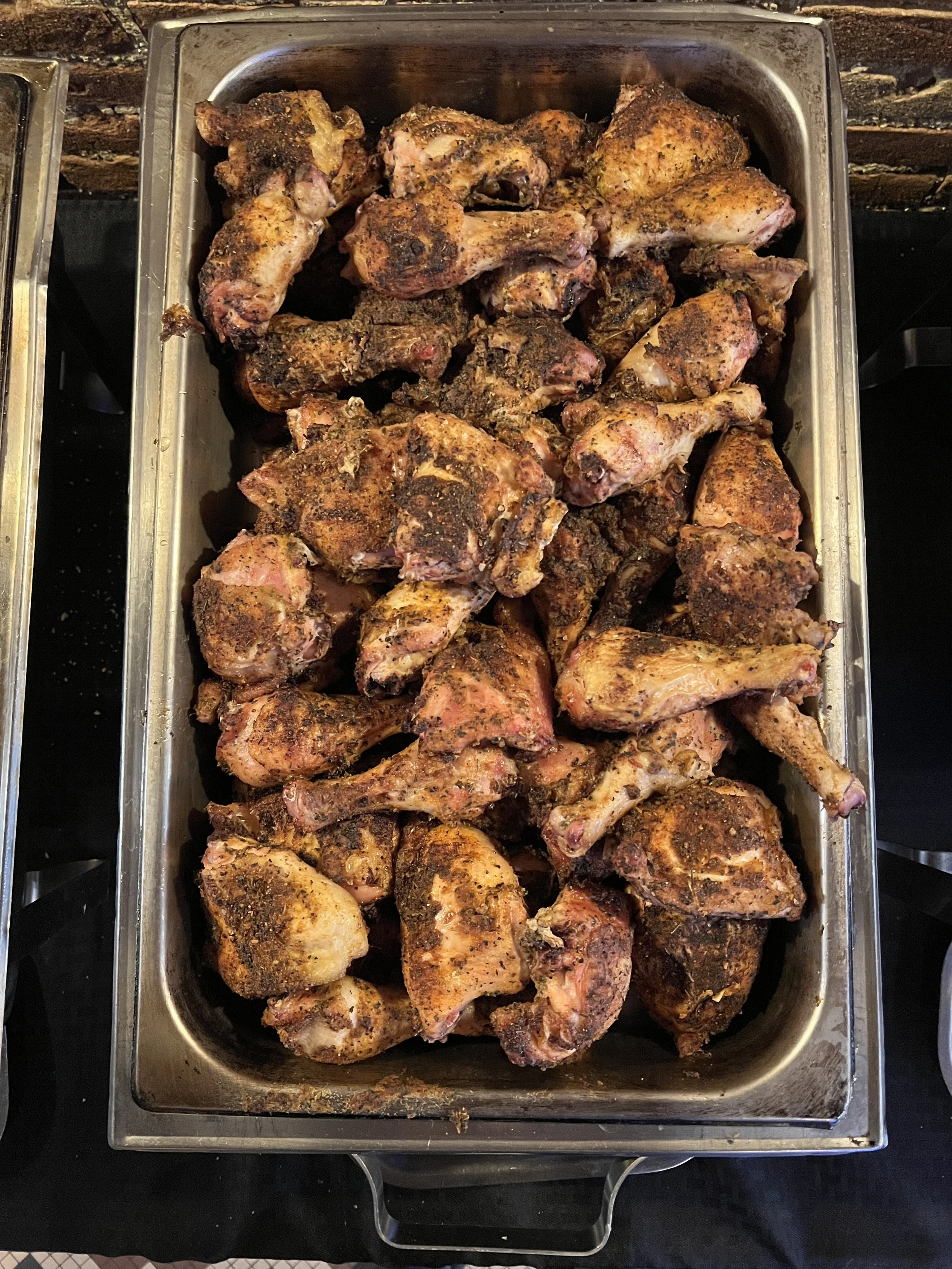 Tray filled with cooked chicken drumsticks seasoned with spices.
