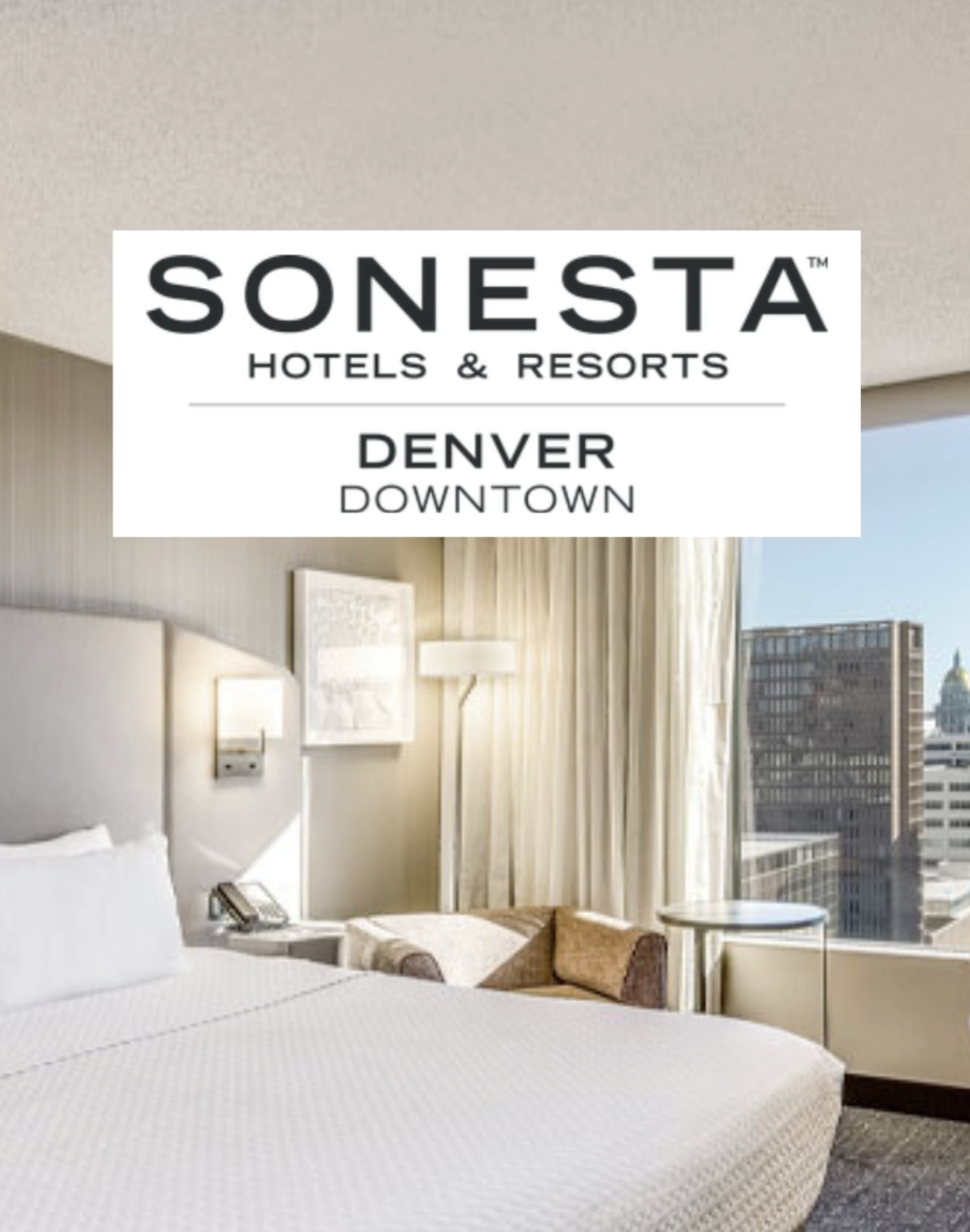 A hotel room with a view of a downtown skyline with the words Sonesta Hotels & Resorts | Denver Downtown on a white box over the photo