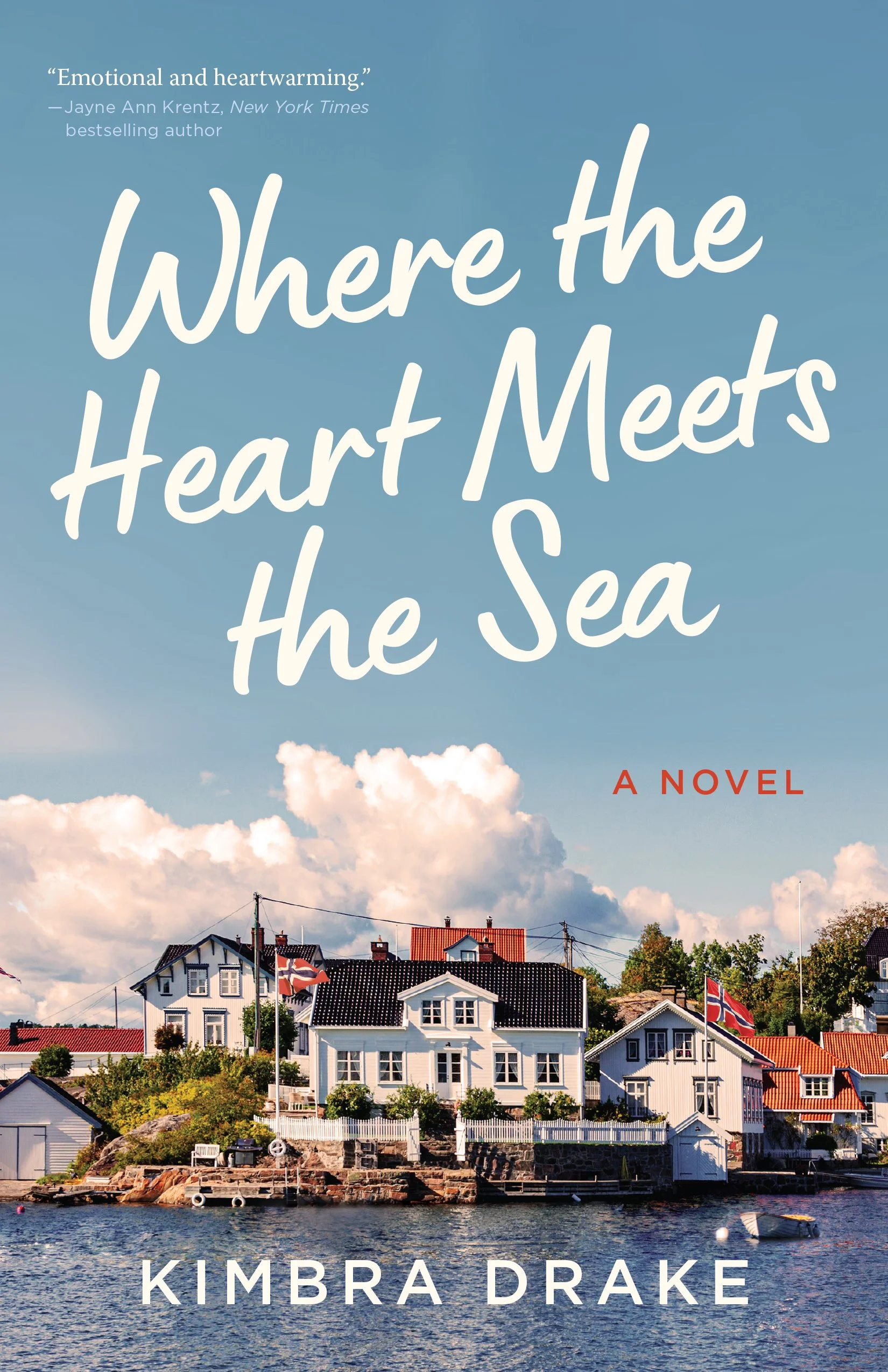 A book cover featuring a group of houses by the water, with a cloudy sky above. The title "Where the Heart Meets the Sea" is prominently displayed along with the author's name, Kimbra Drake, and a quote praising the book.