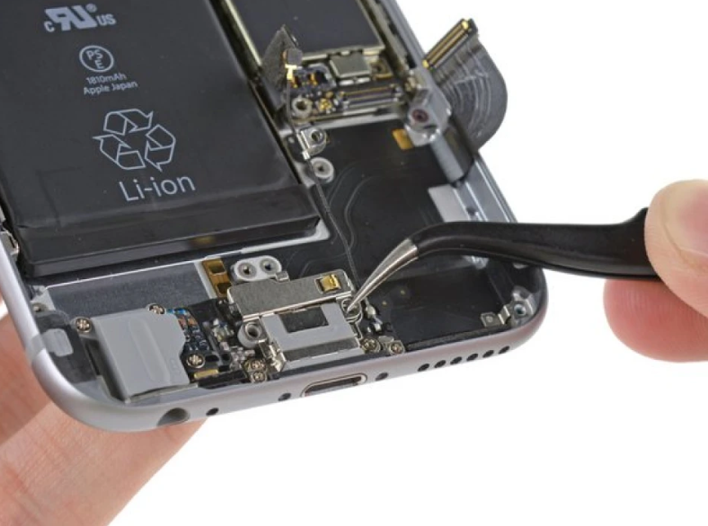 Close-up of a person repairing a smartphone with a small screwdriver, exposing internal components like battery, circuit board, and connectors.