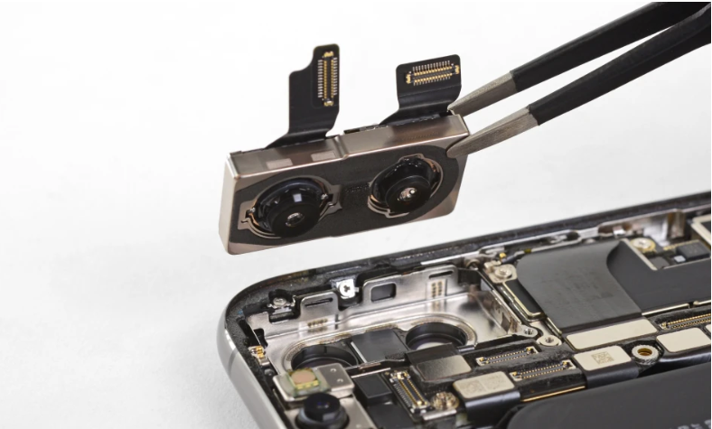 A technician using tweezers to carefully remove or install the camera module from a disassembled smartphone.
