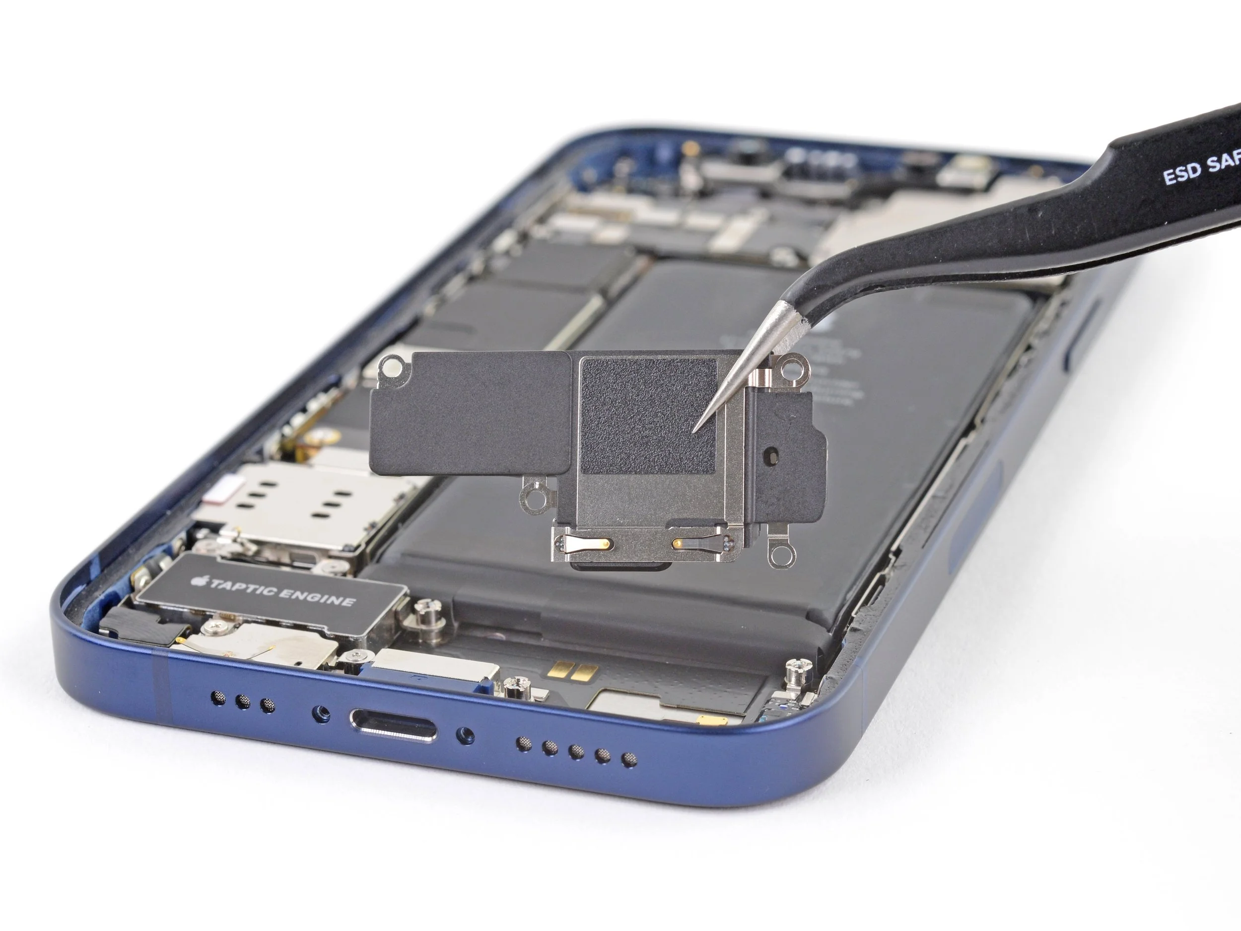 Close-up of a disassembled smartphone with internal components visible, including a tool working on the device.