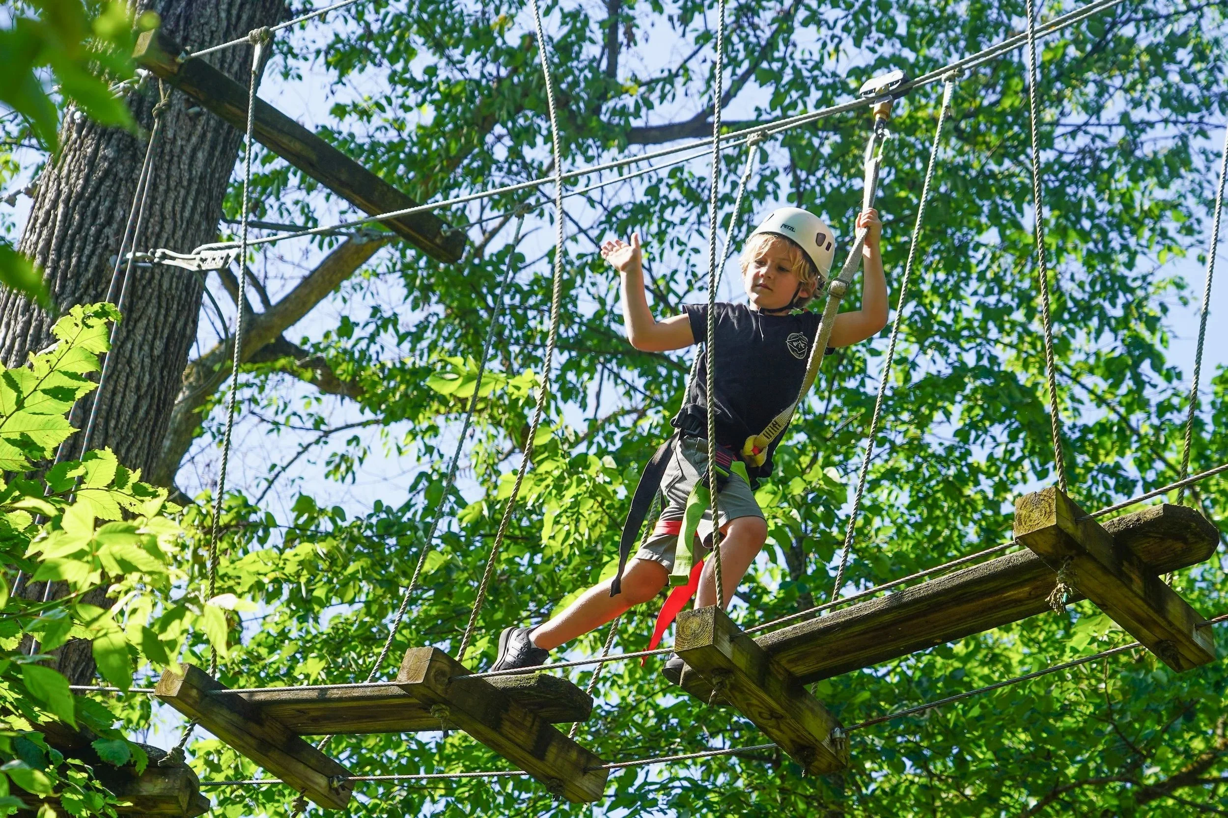 a summer camp student navigating the ropes course near the Wissahickon Creek