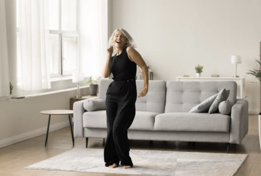 Midlife Woman dancing freely at home representing joy and authentic alignment after identity transition coaching