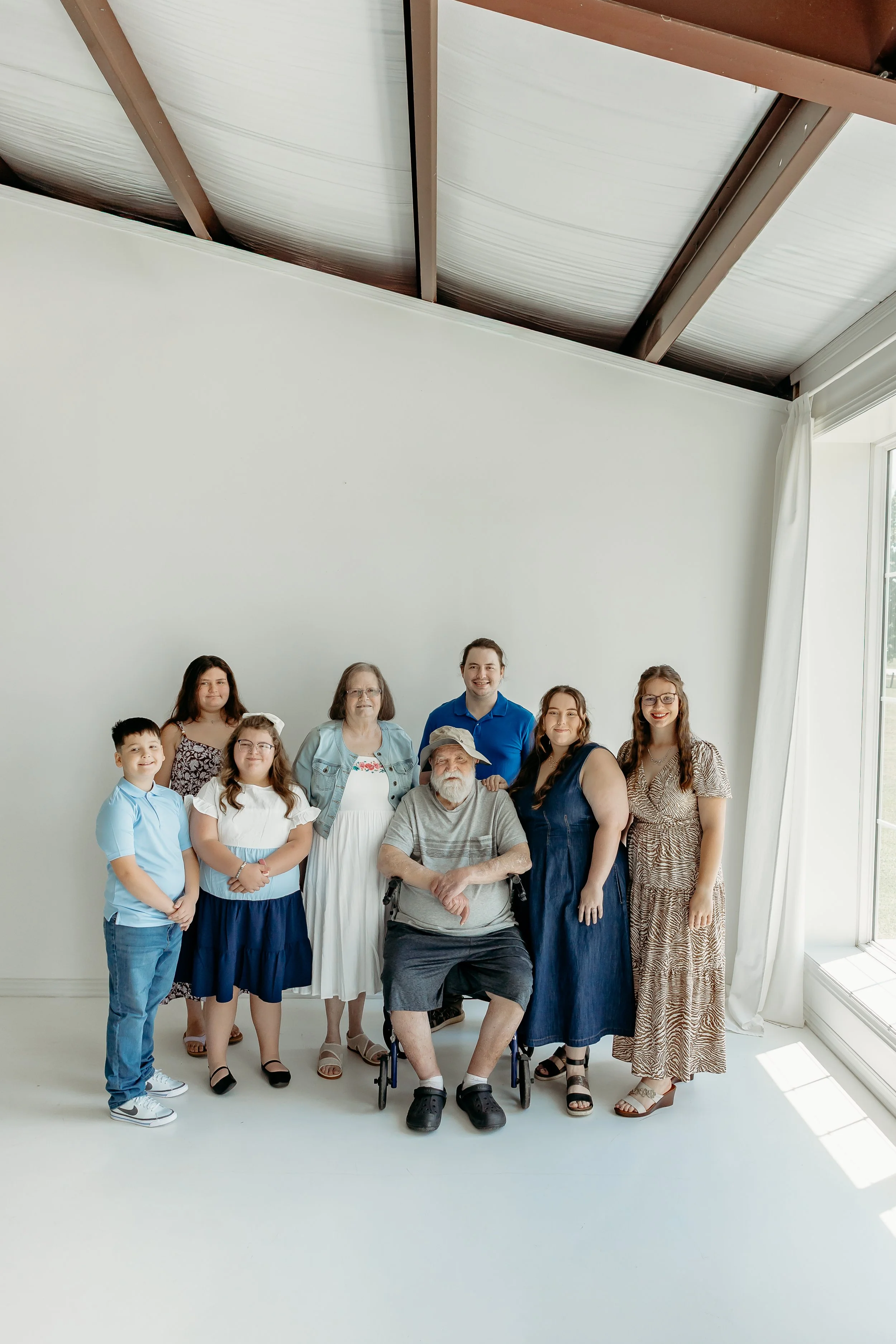 Group of diverse people standing together in a bright room with large windows and white walls.