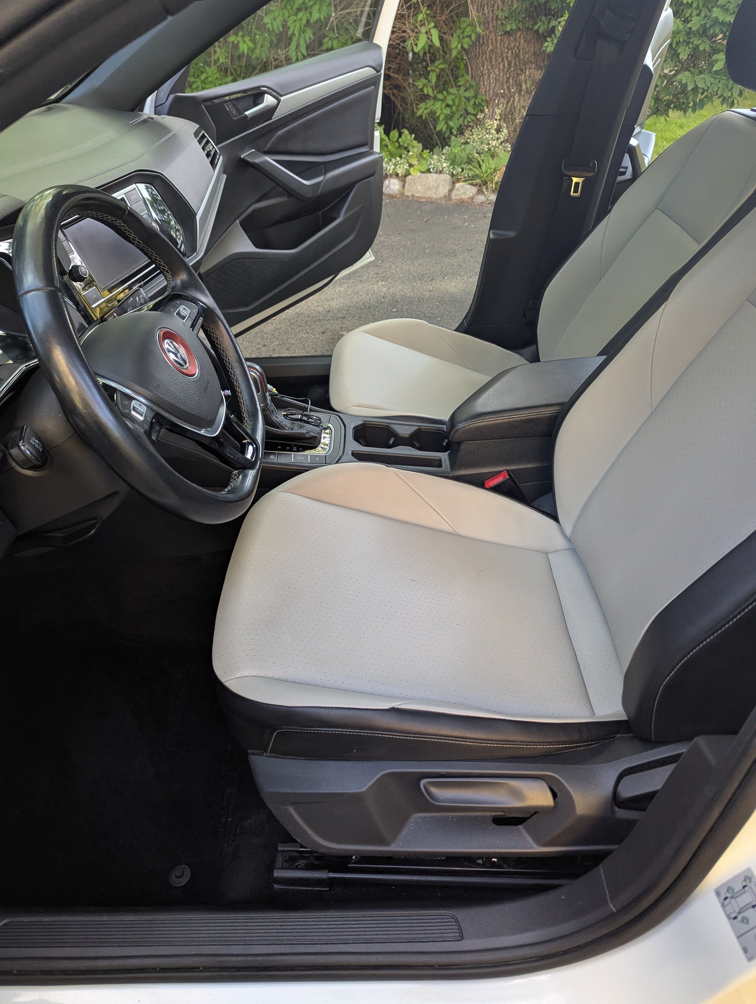 The inside of a vehicle showing the front seats, dashboard, steering wheel, and center console.