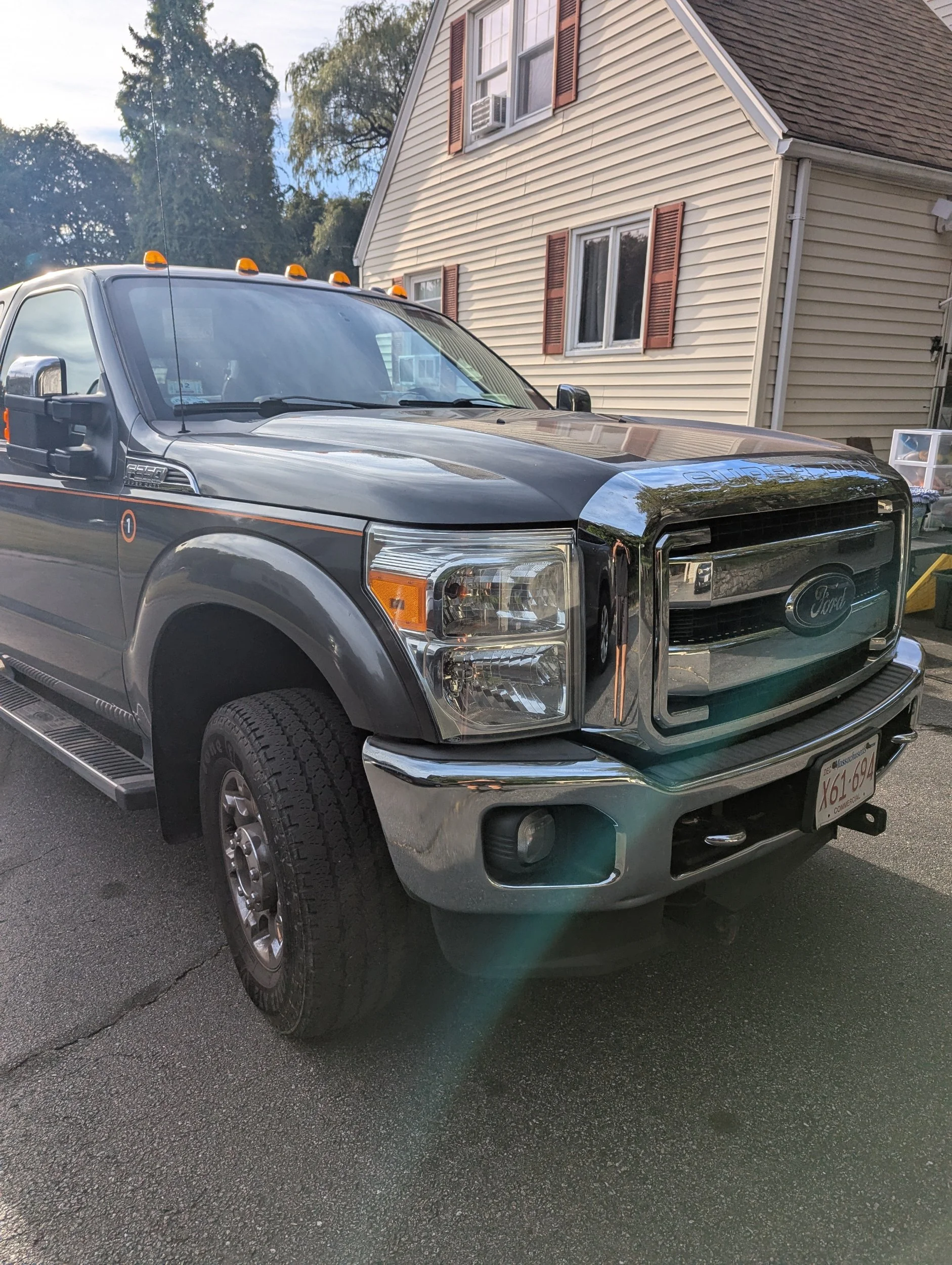 A black Ford F-250 pickup truck parked in front of a beige house with brown shutters during daytime.