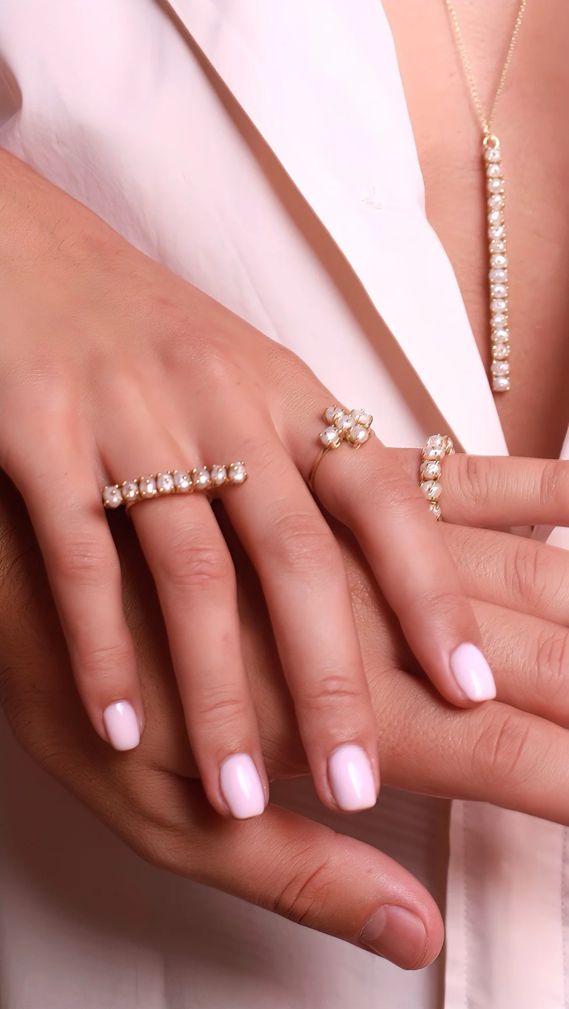 Mains portant des bijoux en or ornés de perles serties sur griffes, avec une femme portant un collier or avec des perles serties sur griffes.