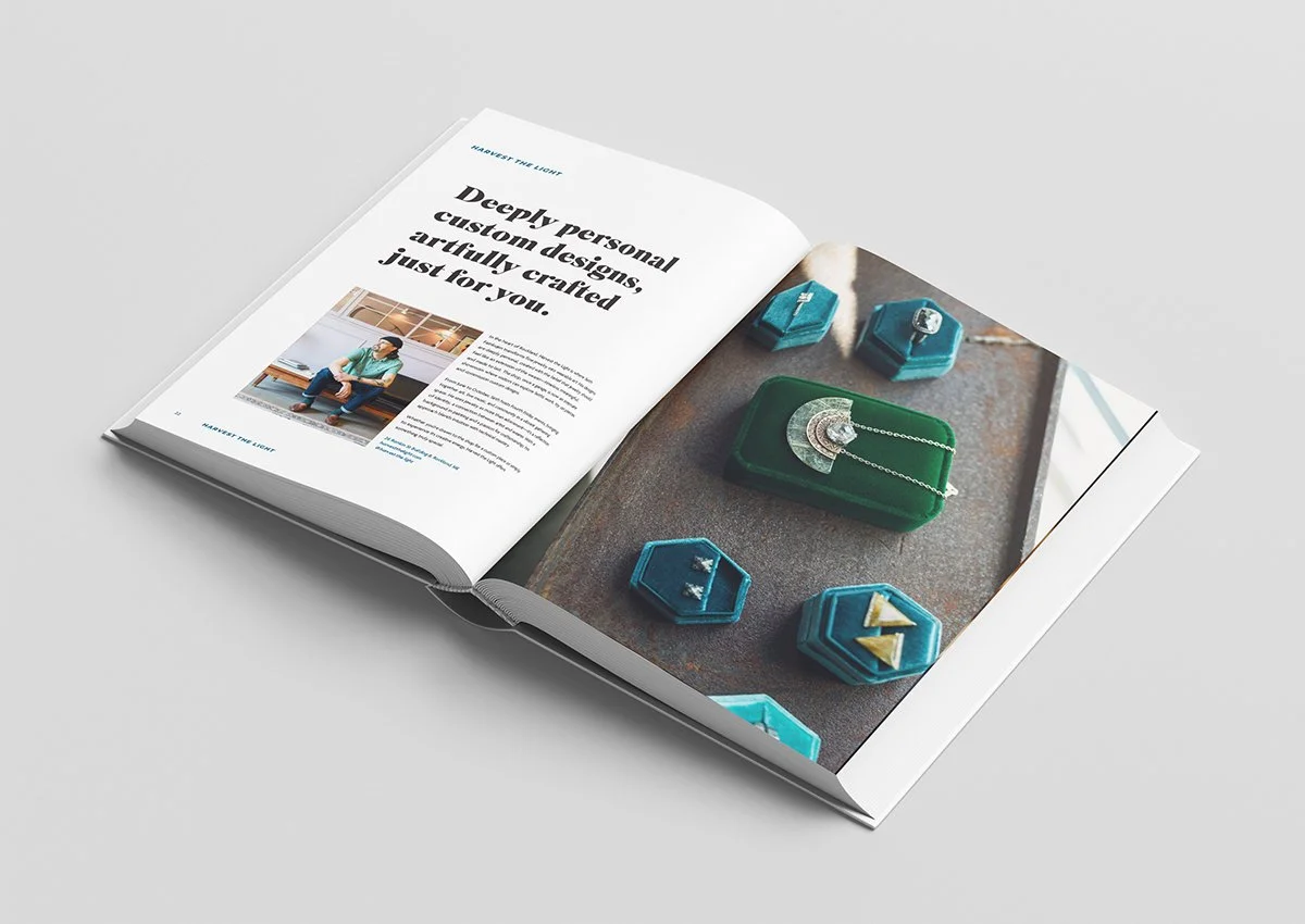 Open magazine displaying jewelry on a textured surface, including necklaces and earrings in blue and green jewelry boxes.