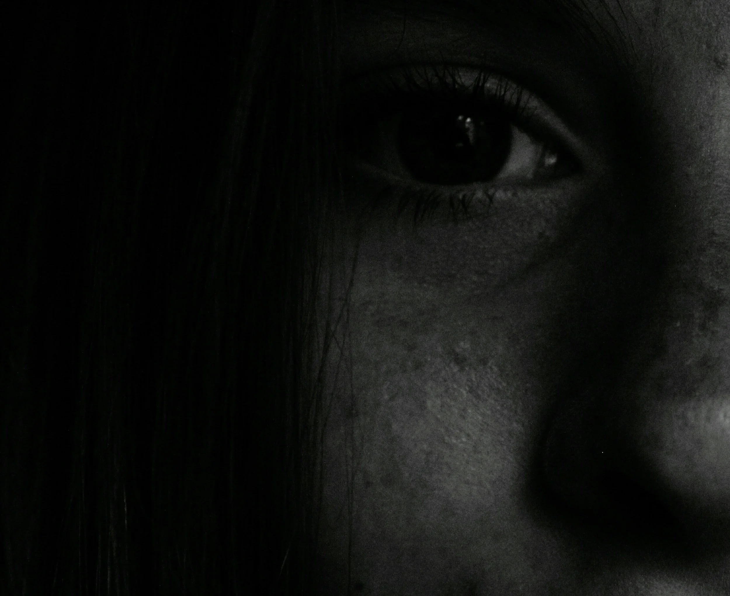 Close-up black and white photo of part of a person's face, focusing on the eye and surrounding facial features.