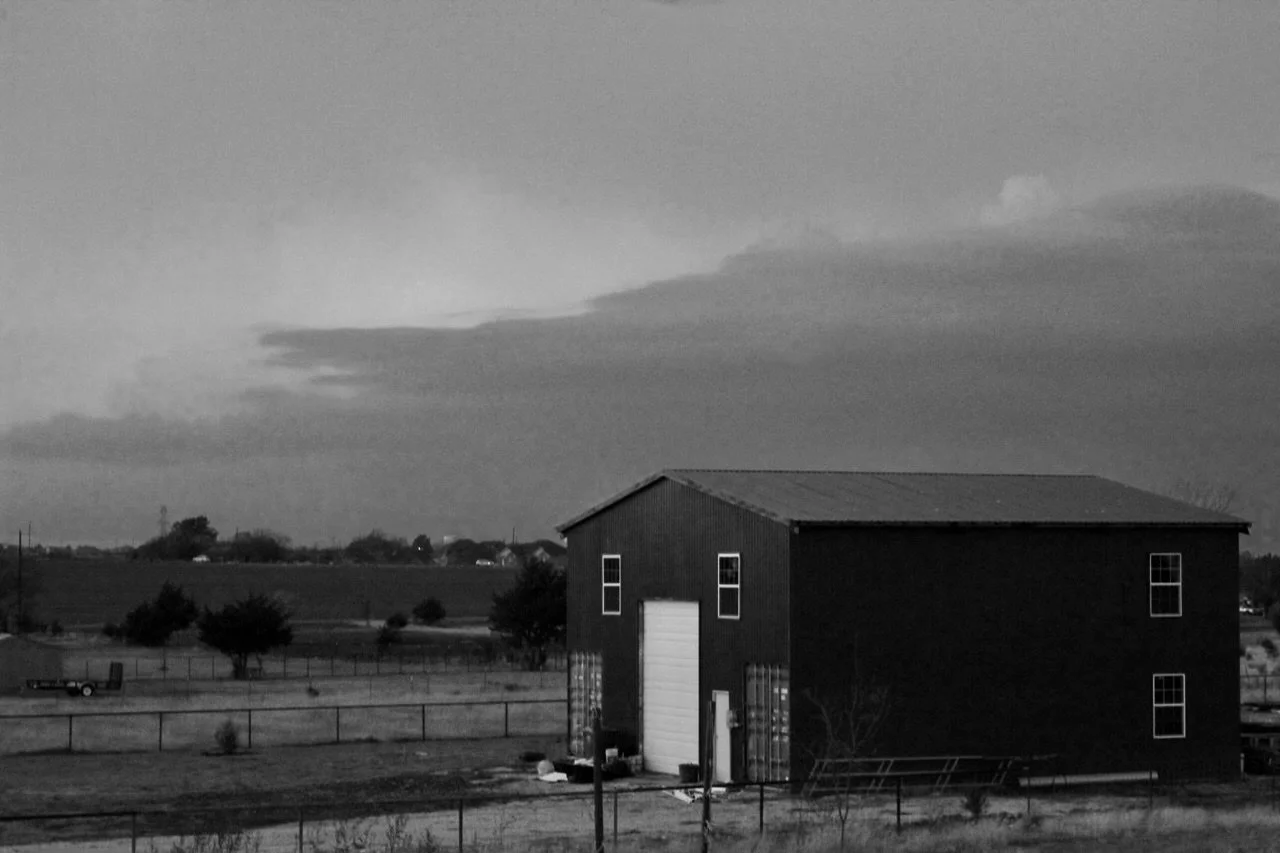 black-and-white photo of a barn against cloudy sky