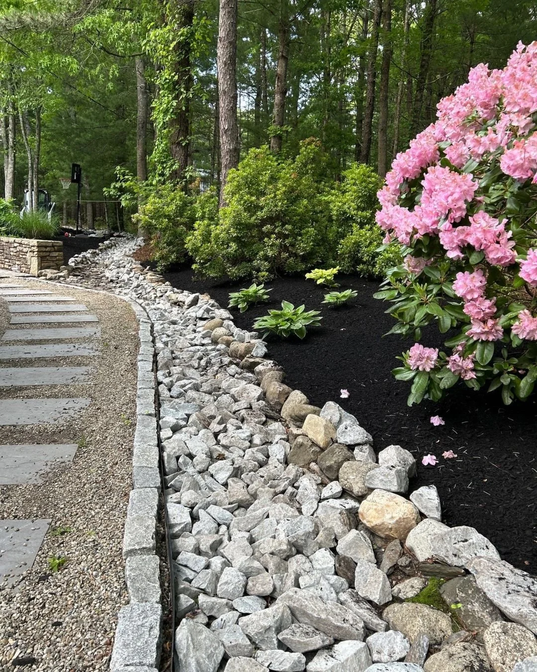 Freshly defined bed lines, healthy plantings, clean stone drainage, and rich mulch make all the difference heading into the warmer months.

A well-designed landscape doesn't just look better, it grows stronger, handles summer heat, and instantly elev